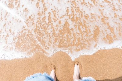 Low section of man on sand at beach