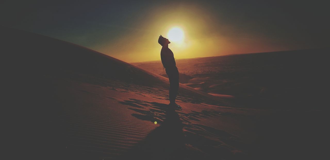 SILHOUETTE MAN STANDING IN SEA AGAINST SUNSET SKY