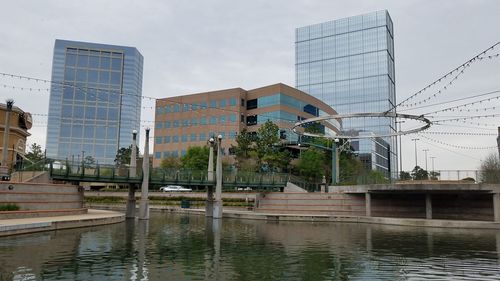 Buildings by canal against sky in city