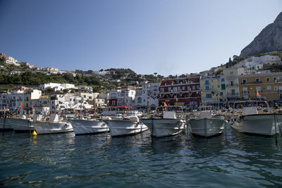 Boats moored on shore against city