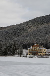 House on snow covered landscape against sky