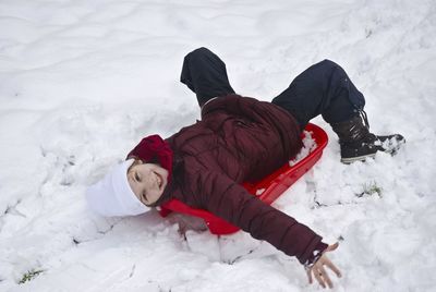 High angle view of child lying down on snow field