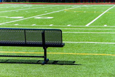 Empty black bench on soccer field during sunny day