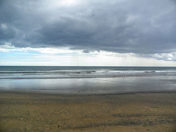 Scenic view of beach against cloudy sky