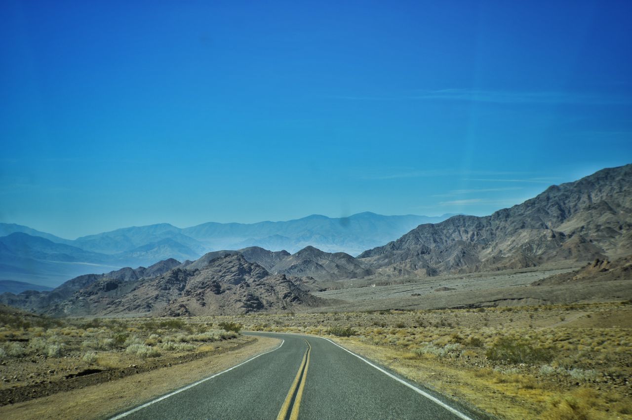 road, the way forward, road marking, transportation, mountain, nature, tranquil scene, tranquility, landscape, scenics, no people, white line, day, beauty in nature, empty, solitude, blue, outdoors, mountain range, remote, dividing line, clear sky, winding road, sky