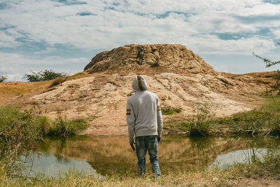 Rear view of man looking at waterfall against sky