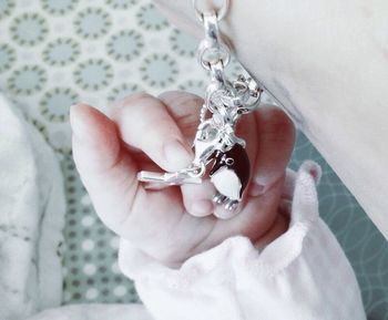 Cropped image of baby girl holding cross bracelet