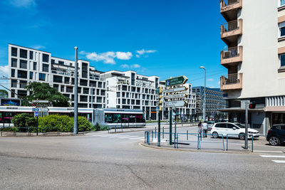 Road by buildings against sky in city