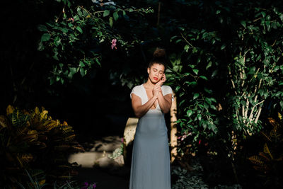 Portrait of smiling young woman standing by plants