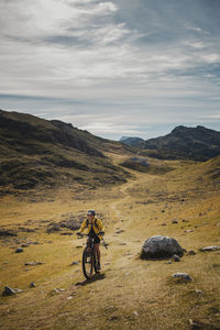 Woman riding electric bicycle on mountain at somiedo natural park, spain