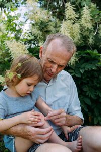 A little girl hugs her grandfather on a walk in the summer outdoors.