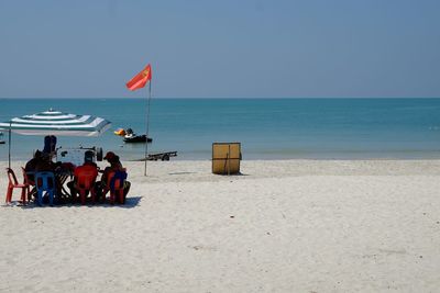 People at beach against clear sky