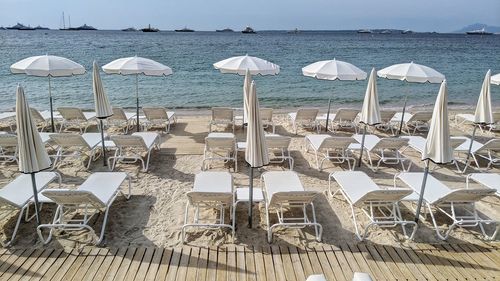 Deck chairs and parasols on beach against sky