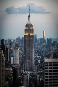 Modern buildings in city against cloudy sky