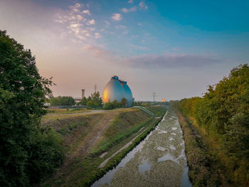 Road by canal against sky