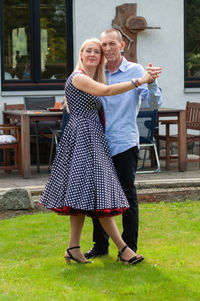 Beautiful young couple of newlyweds dancing tango on the lawn in the garden