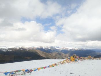 Colorful bunting on snowcapped mountain against cloudy sky