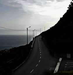 Road by silhouette mountain against sky