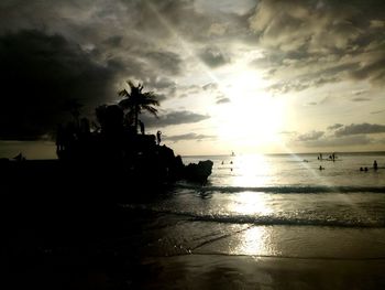 Silhouette people on beach against sky during sunset