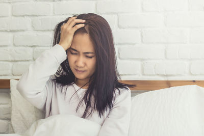 Portrait of young woman against wall