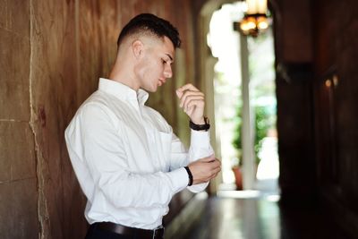 Side view of young man fixing his sleeve