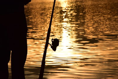 Silhouette of man standing in sea during sunset