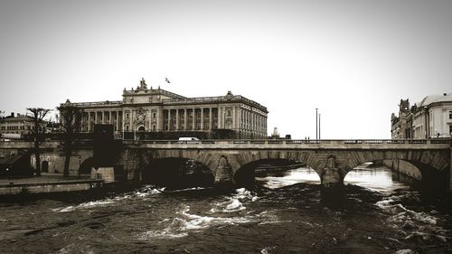 Bridge over river in city against clear sky