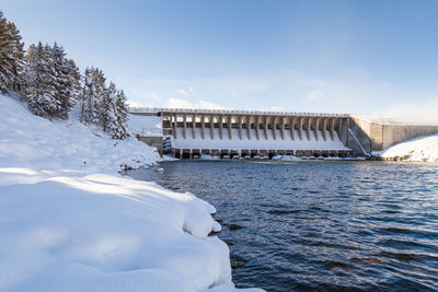 Bridge over river against sky during winter
