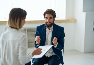 Portrait of businessman using mobile phone while standing in office