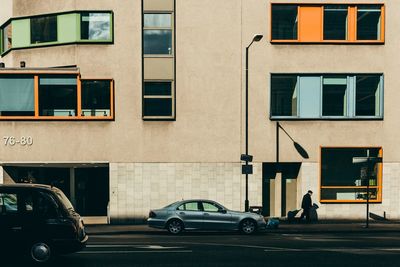 Cars on road by building in city