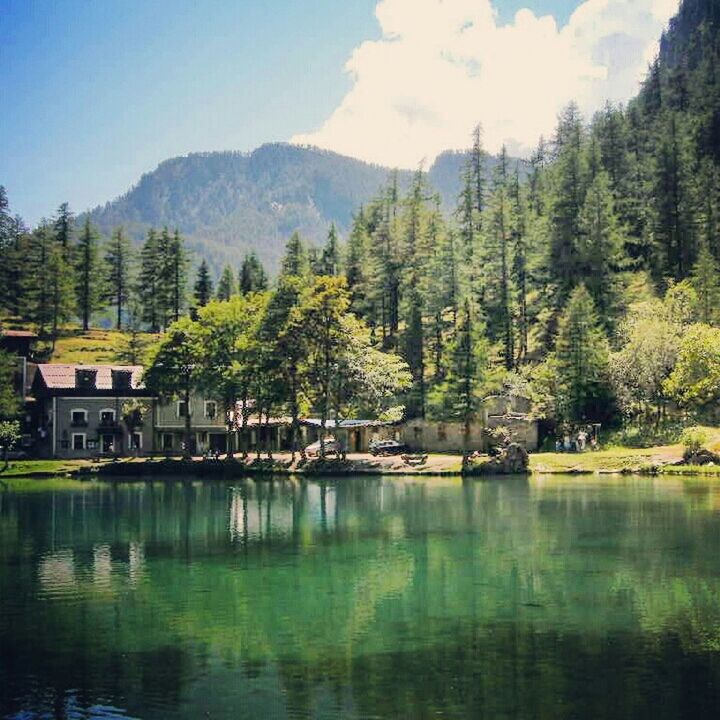 tree, water, mountain, lake, reflection, tranquil scene, tranquility, waterfront, scenics, beauty in nature, nature, mountain range, clear sky, river, idyllic, house, building exterior, built structure, sky, non-urban scene