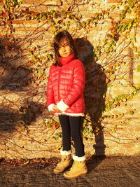 Full length portrait of girl standing against wall 