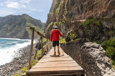 Rear view of man standing on rock by water