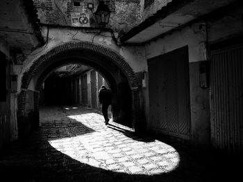 Rear view of man walking on street amidst buildings