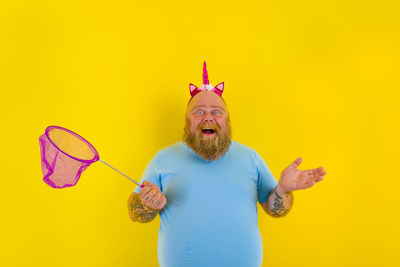 Portrait of man standing against yellow background