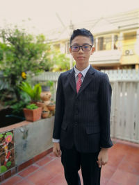 Portrait of boy wearing eyeglasses while standing against house
