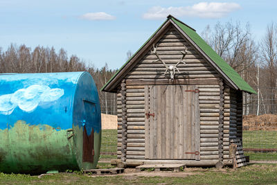 Log shed with deer antlers above the door in the yard of a farm