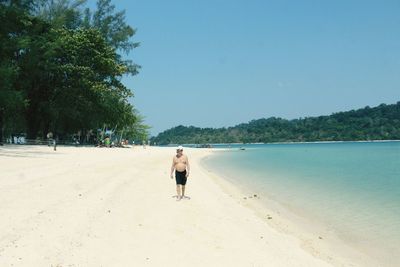 Rear view of woman walking on beach against sky