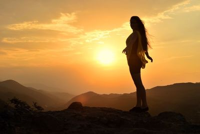 Silhouette woman standing on mountain against sky during sunset