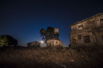 Low angle view of abandoned house on field against sky at night