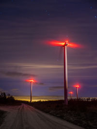 Windturbines on field against sky at night