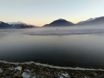 Scenic view of frozen lake against mountains during sunset