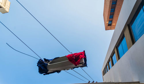 Low angle view of flags hanging against clear blue sky