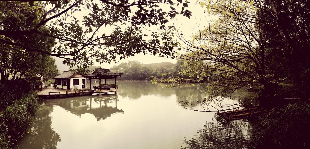 architecture, water, built structure, tree, building exterior, reflection, river, waterfront, canal, sky, bare tree, lake, branch, bridge - man made structure, nature, house, connection, tranquility, day, outdoors