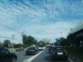 Cars on street against cloudy sky