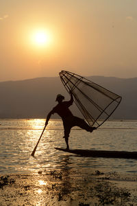 Man fishing in lake at sunset