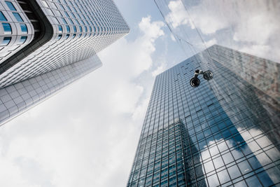 Directly below shot of modern glass building against cloudy sky