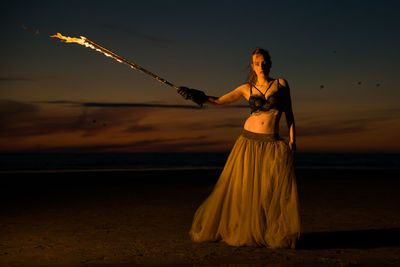 Woman standing at beach during sunset