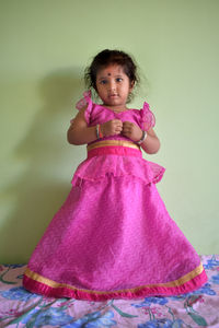 Portrait of cute girl standing against pink background