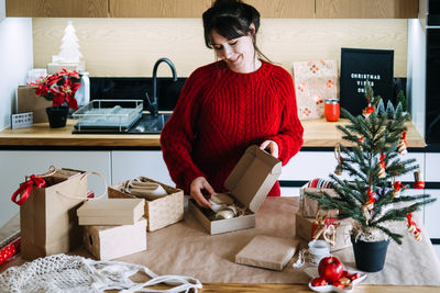 Rear view of woman using digital tablet while sitting on table